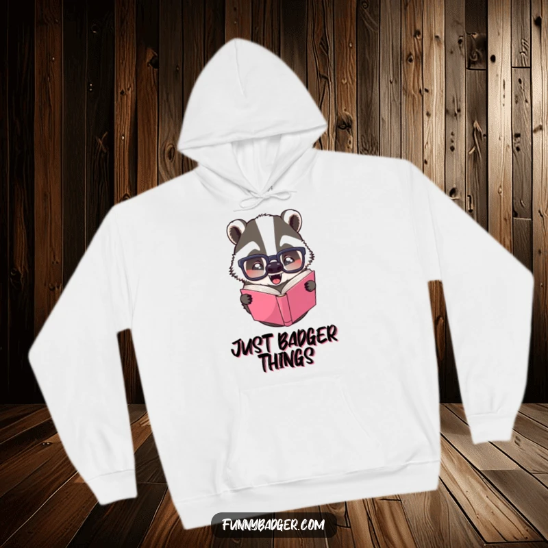 Funny hoodie with a cozy badger wearing large glasses, looking confused while reading a book upside down, perfect for comfort.